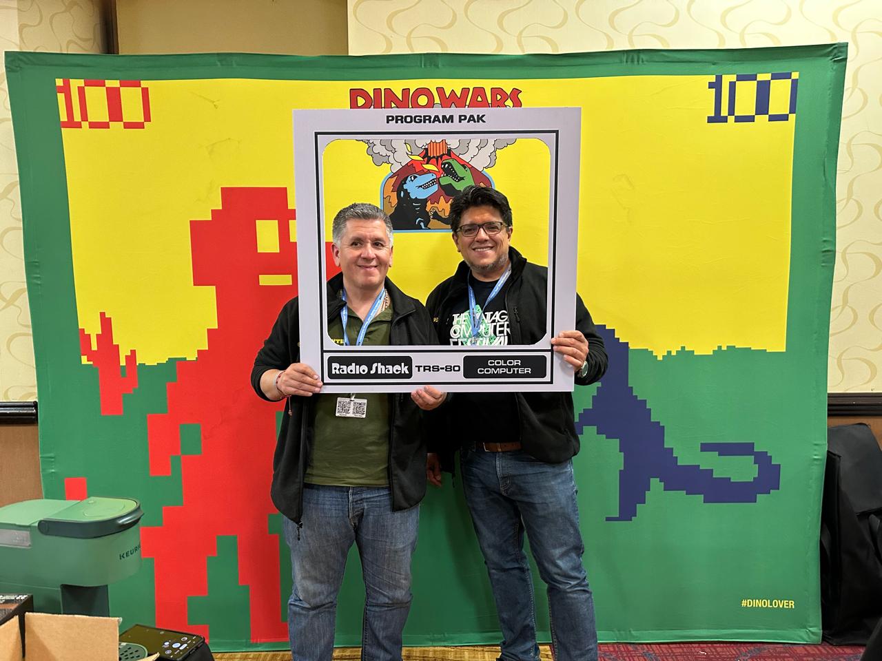 CoCoByte members at a Vintage Computer Festival in front of a Dino Wars / Radio Shack TRS-80 Color Computer backdrop